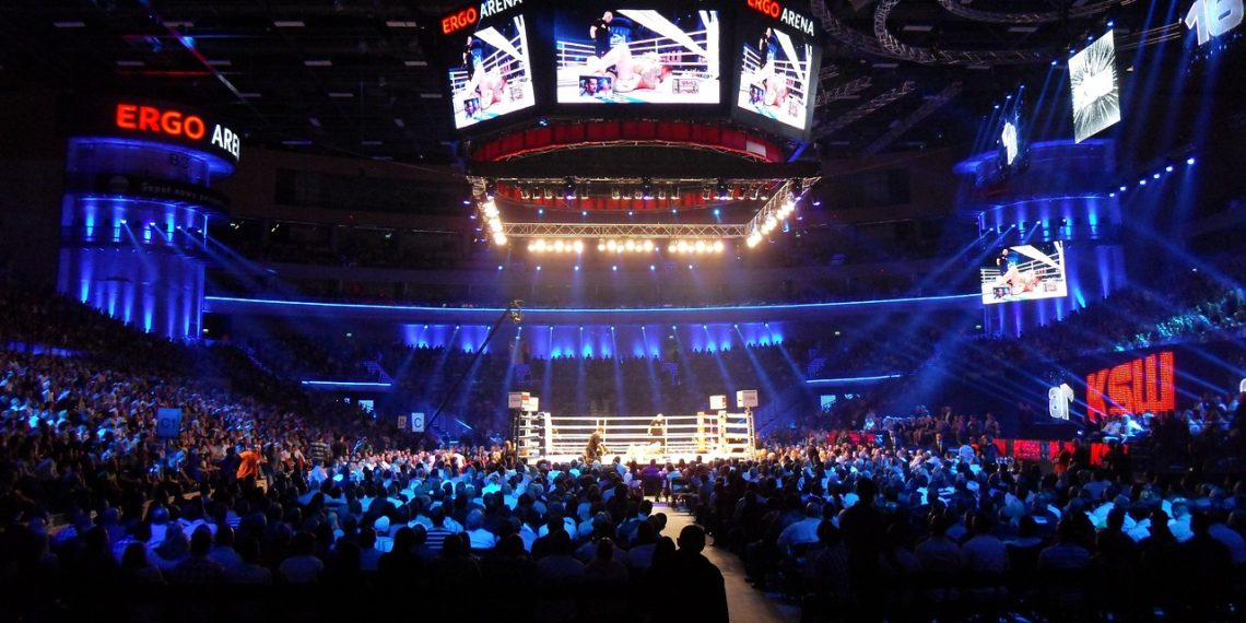 A boxing ring under bright lights in a packed indoor arena