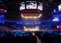 A boxing ring under bright lights in a packed indoor arena