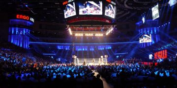 A boxing ring under bright lights in a packed indoor arena