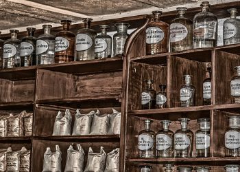Tins of food and bottles of water stacked on a kitchen shelf
